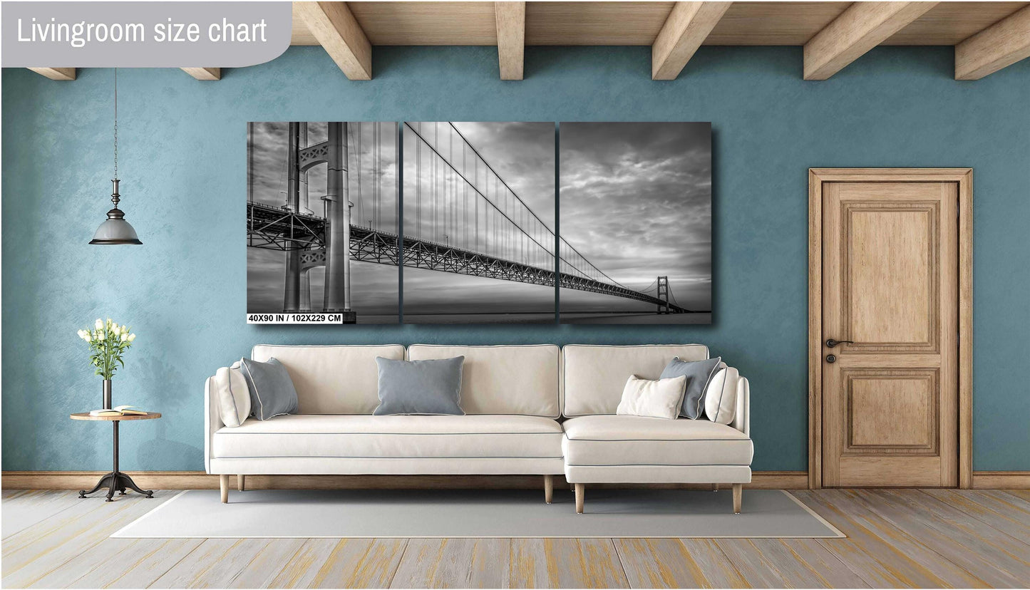 A black and white photograph of the Mackinac Bridge, capturing the engineering and grandeur of the structure with a backdrop of overcast sky and a body of water in a living room for size chart.