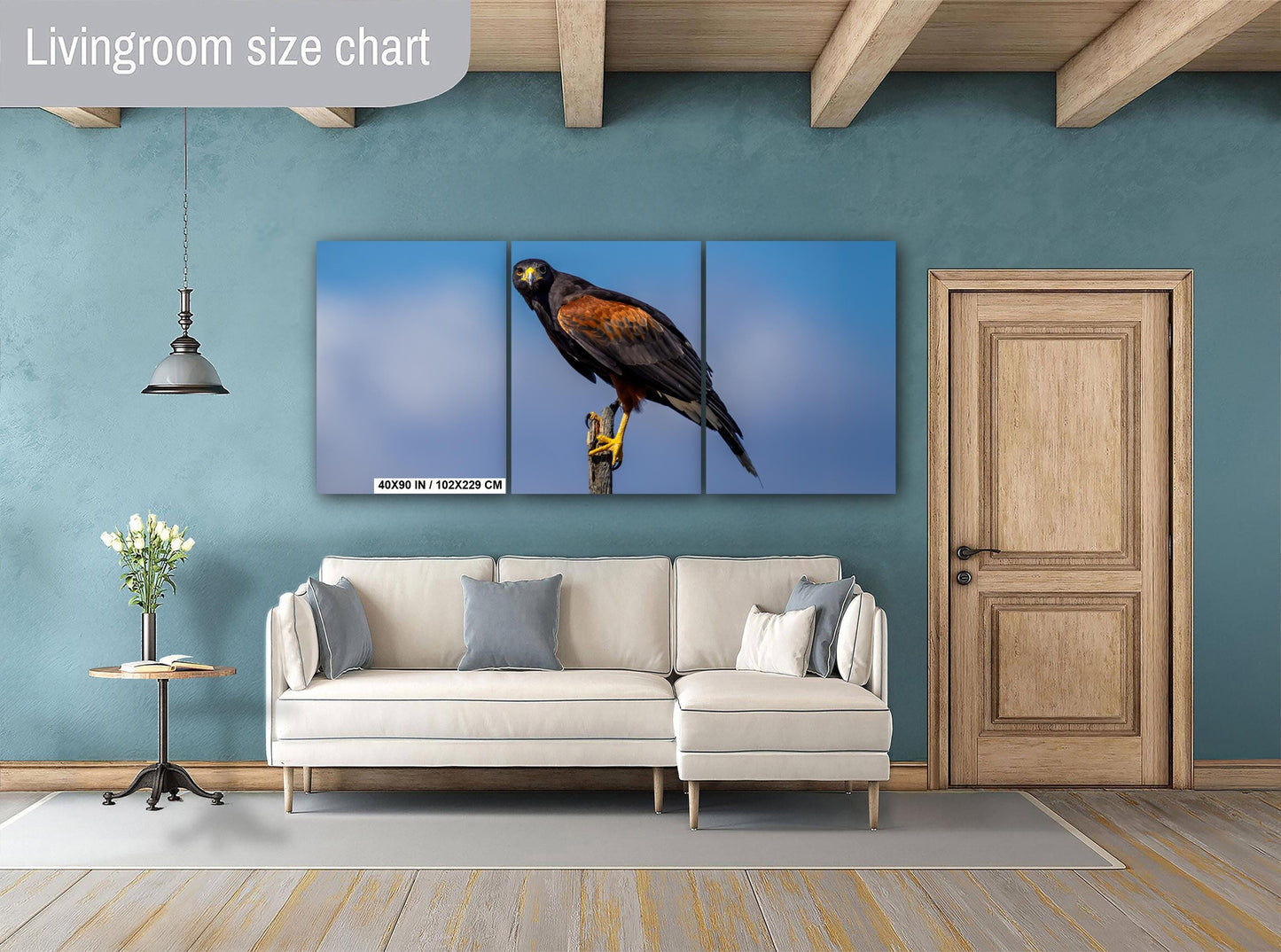 Living room with a large wall art of a hawk on a blue background, light gray sofa, and wooden door.