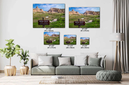 Living room with a sofa and decorative plants, featuring wall art prints of a scenic landscape.