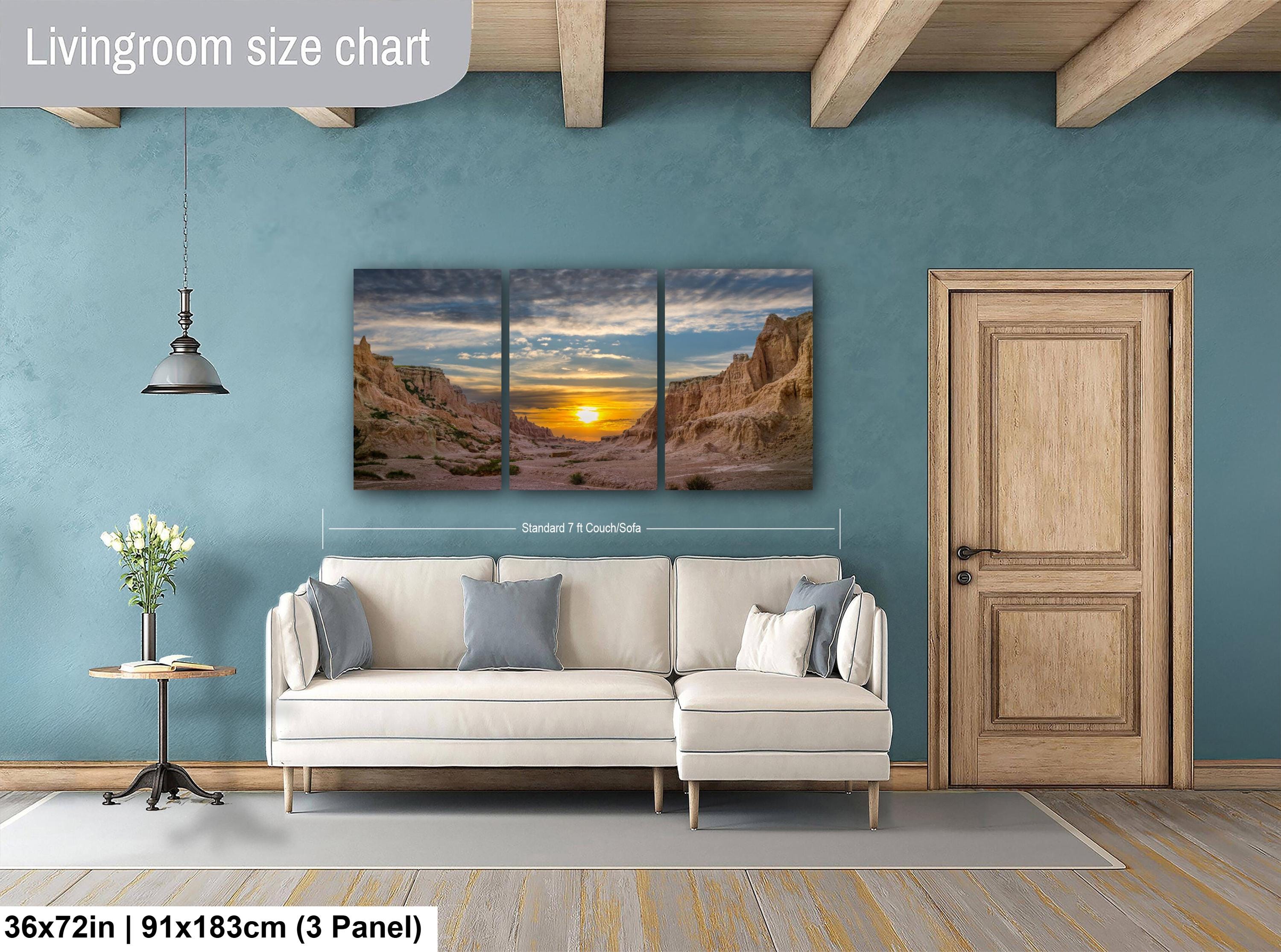 Living room with a beige sofa, side table, and wall art depicting a sunset over a mountain range.