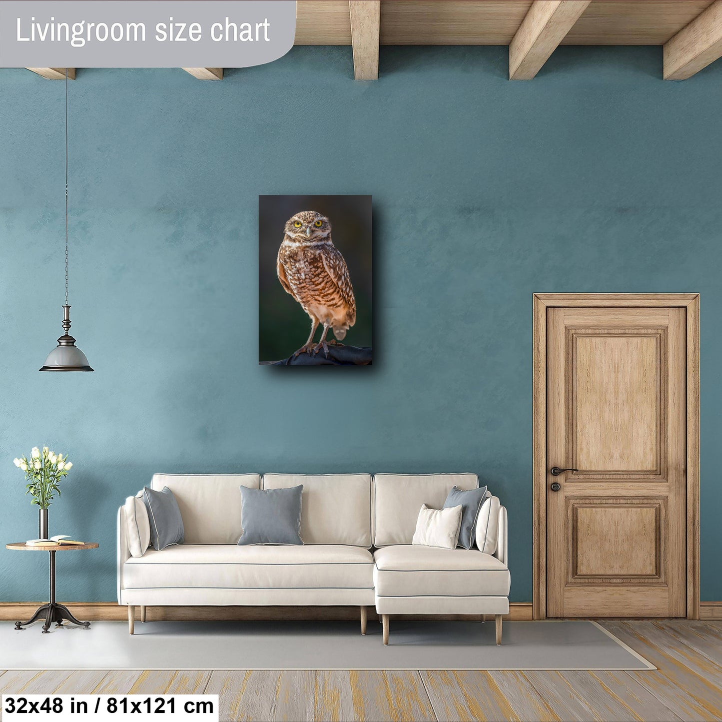 a living room with a large painting of an owl hanging on the wall. The room has a white sofa and a wooden door, creating a cozy and inviting atmosphere.
