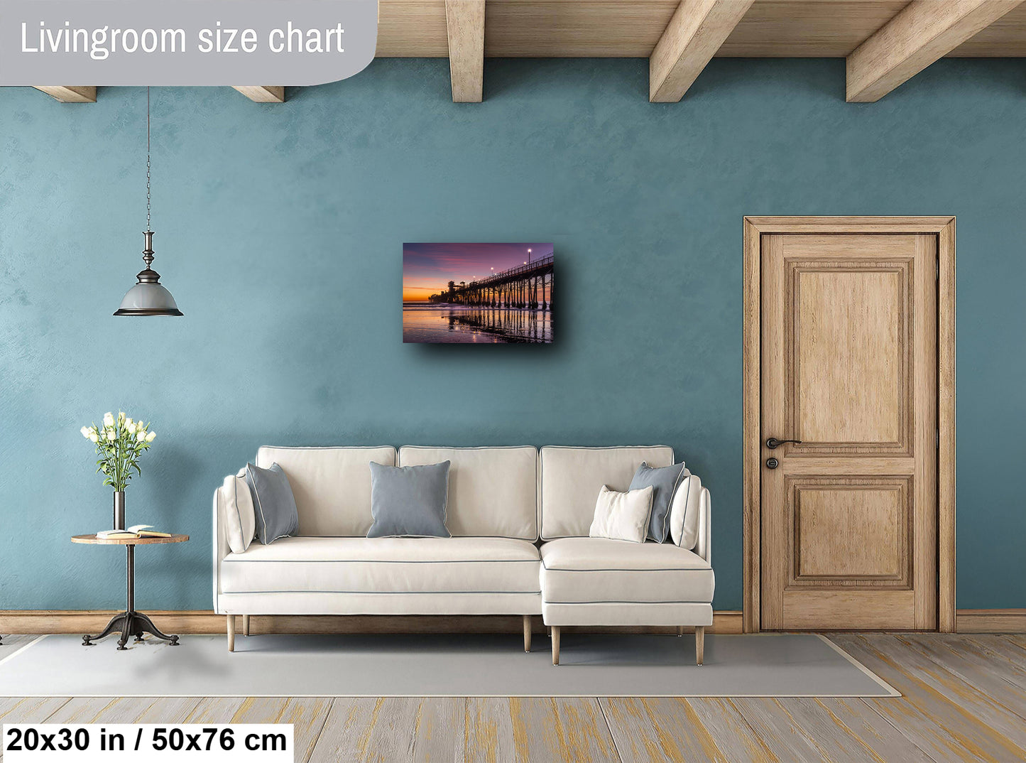 a living room with a white sofa, a wooden door, and a painting of a pier on the wall.