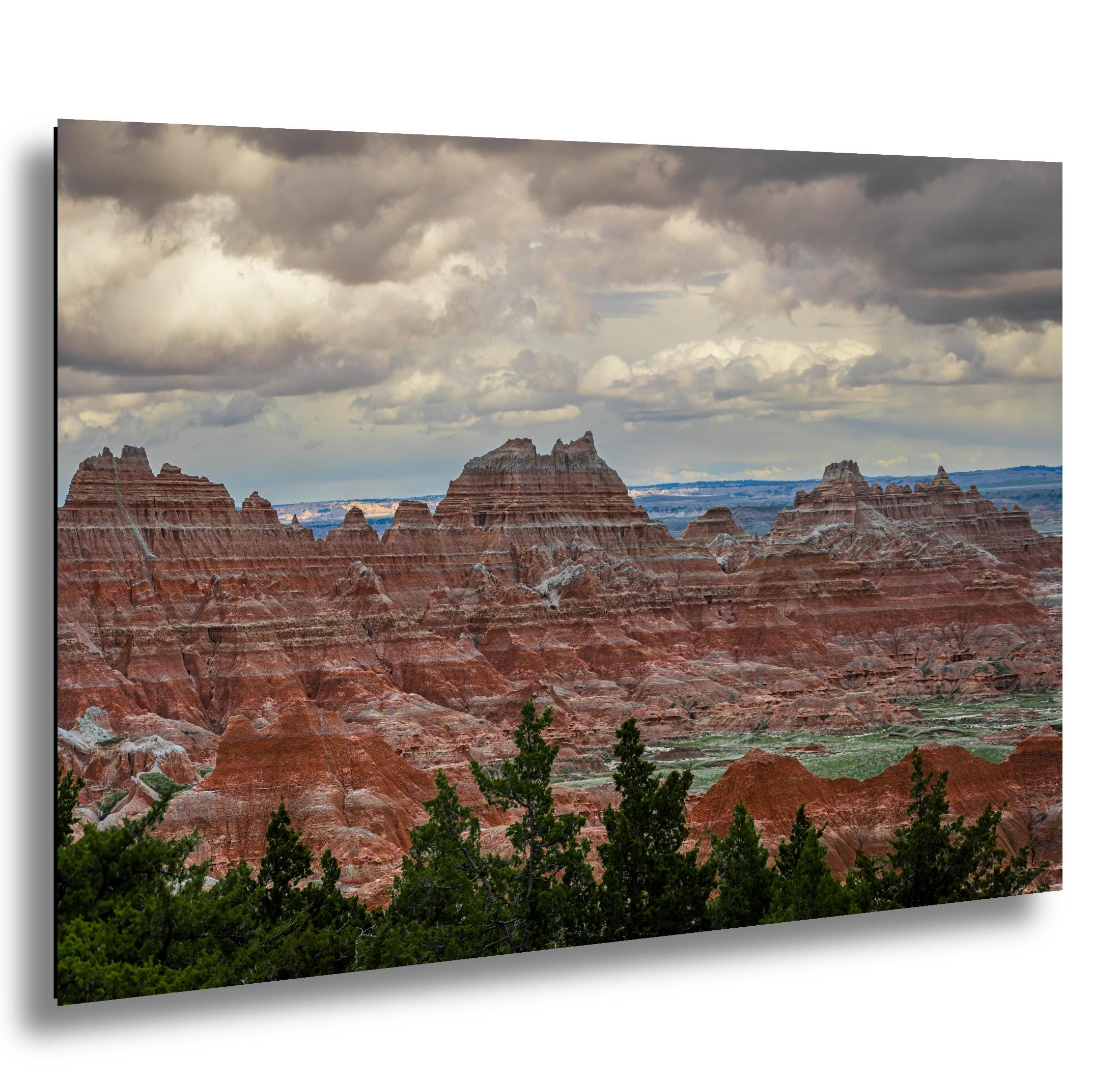 Badlands National Park red rock formations under storm clouds with green pines in the foreground