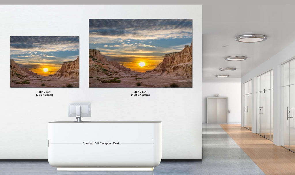 Two large wall art prints of a desert sunset in an office setting.