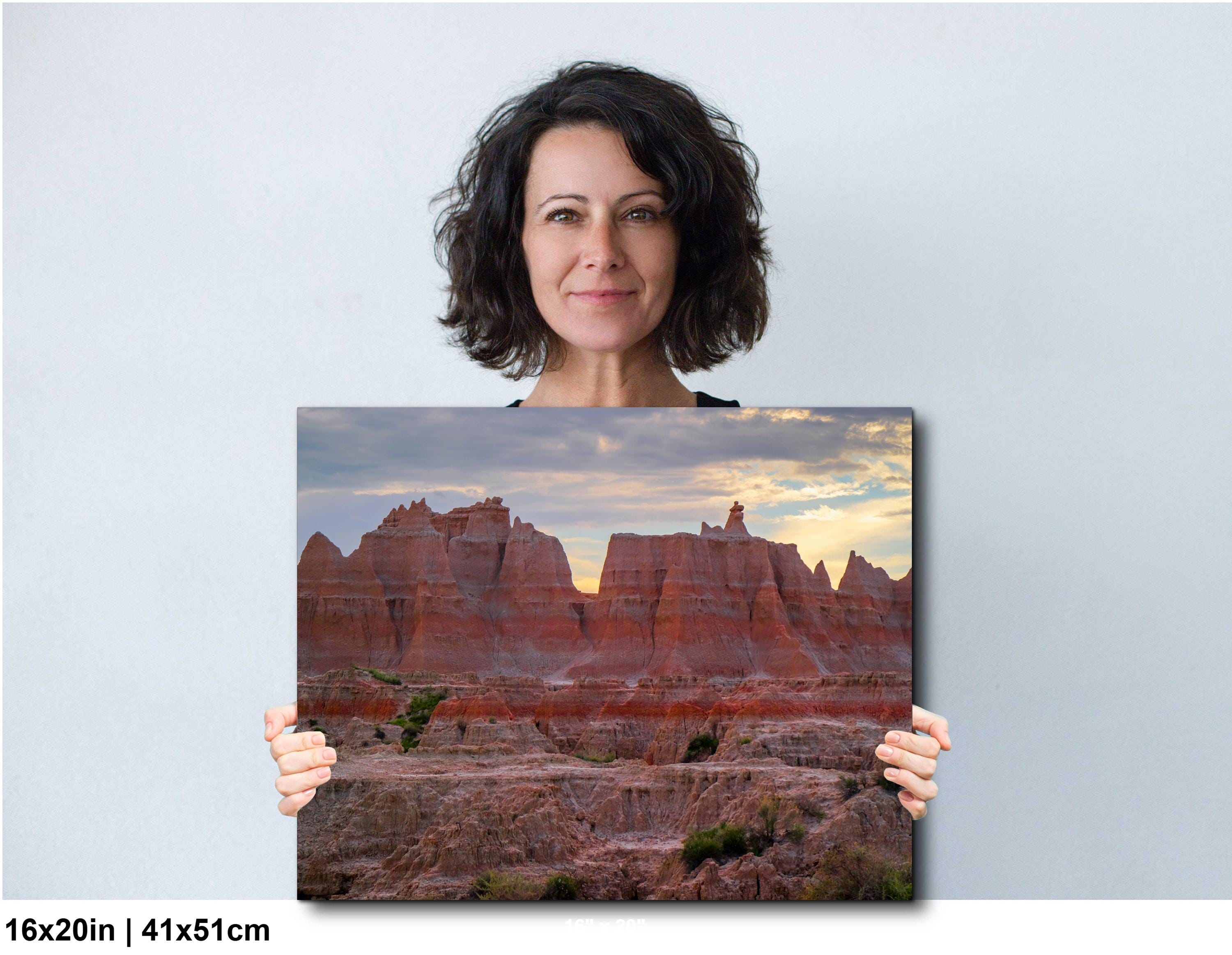 Woman holding a photograph of a desert landscape with red rock formations.