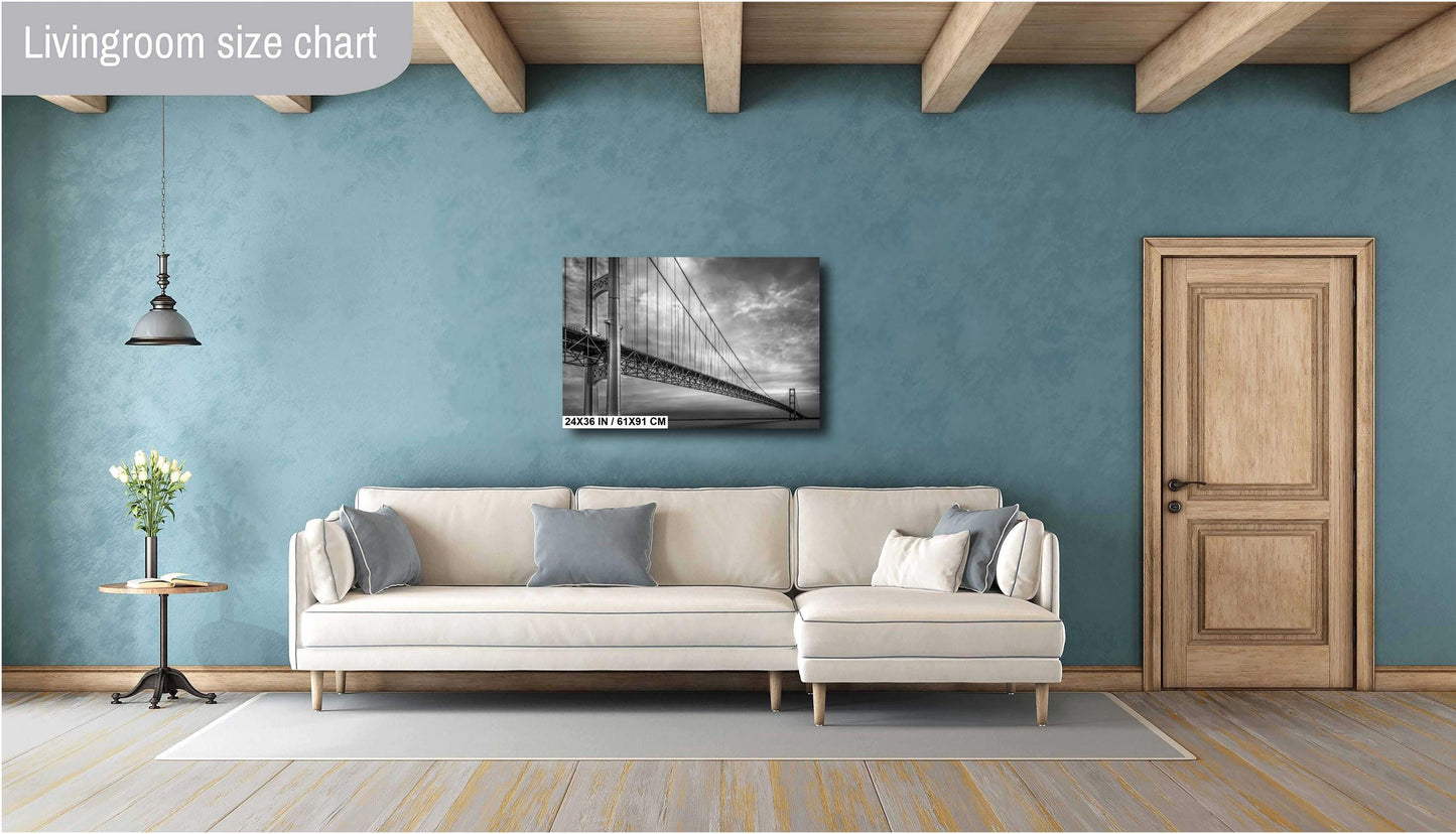 A black and white photograph of the Mackinac Bridge, capturing the engineering and grandeur of the structure with a backdrop of overcast sky and a body of water.