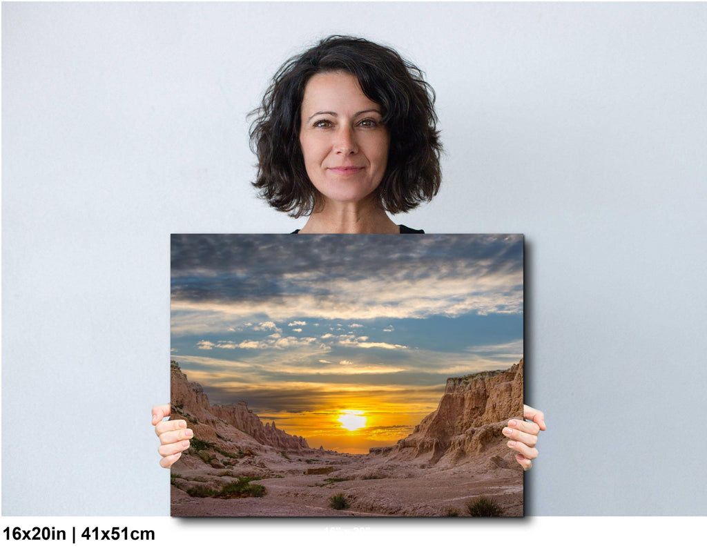 Woman holding a photograph of a sunset over a desert landscape