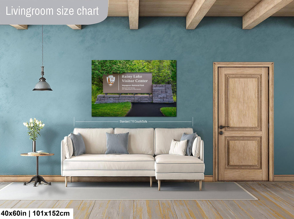 Living room with a wall art displaying rainy lake visitor center sign, beige sofa, and wooden door.