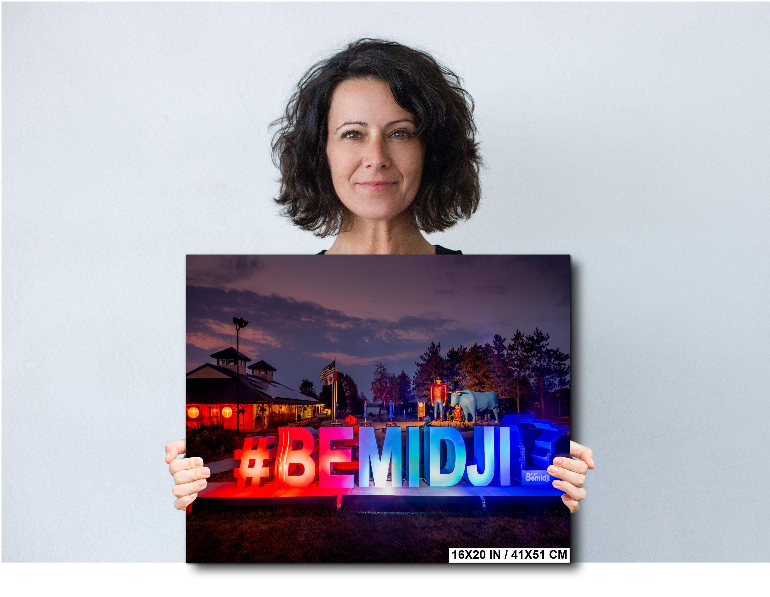 Woman holding a photo print with colorful text against a plain background
