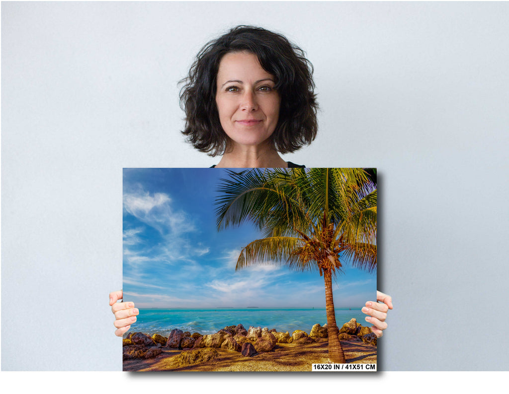 Woman holding a print of a tropical beach scene with a palm tree in Key West.