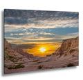 Badlands National Park canyon cliffs at sunset with glowing golden sky.