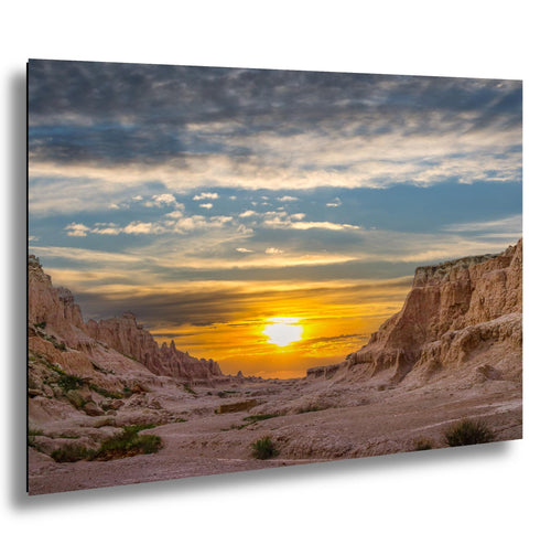 Badlands National Park canyon cliffs at sunset with glowing golden sky.