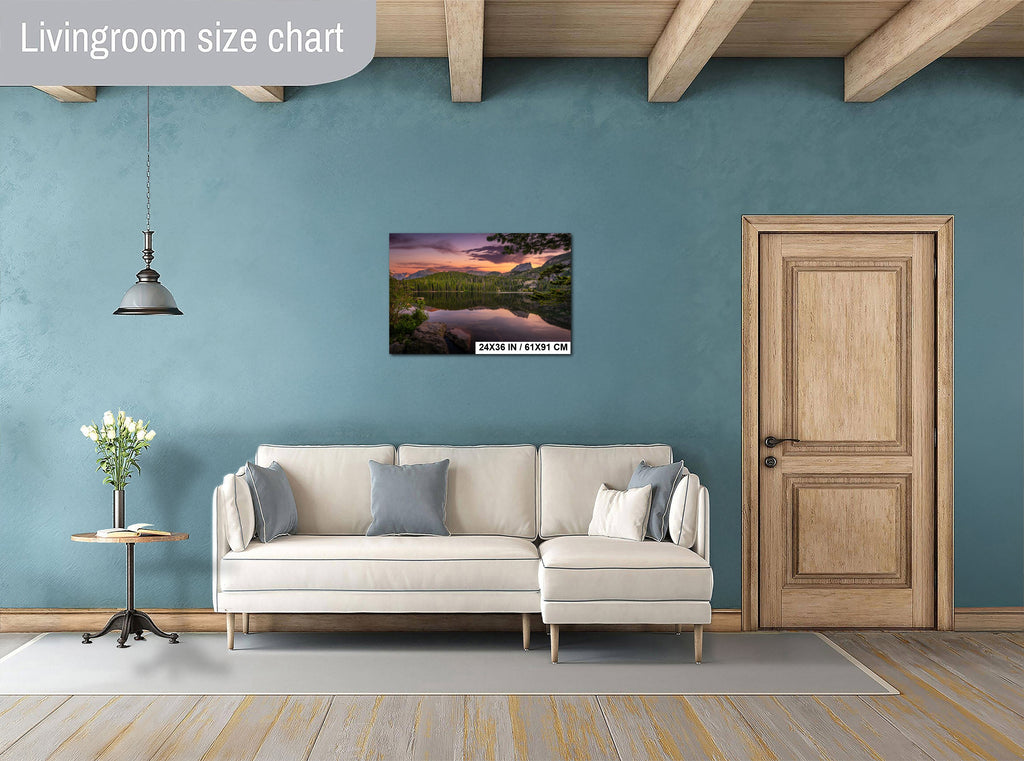 a living room with a white sofa, a wooden door, and a painting of a sunset landscape on the wall.