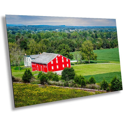 A wall art print featuring a red barn in a rural landscape with green fields and trees in McLean Farm in Adams County, Pennsylvania