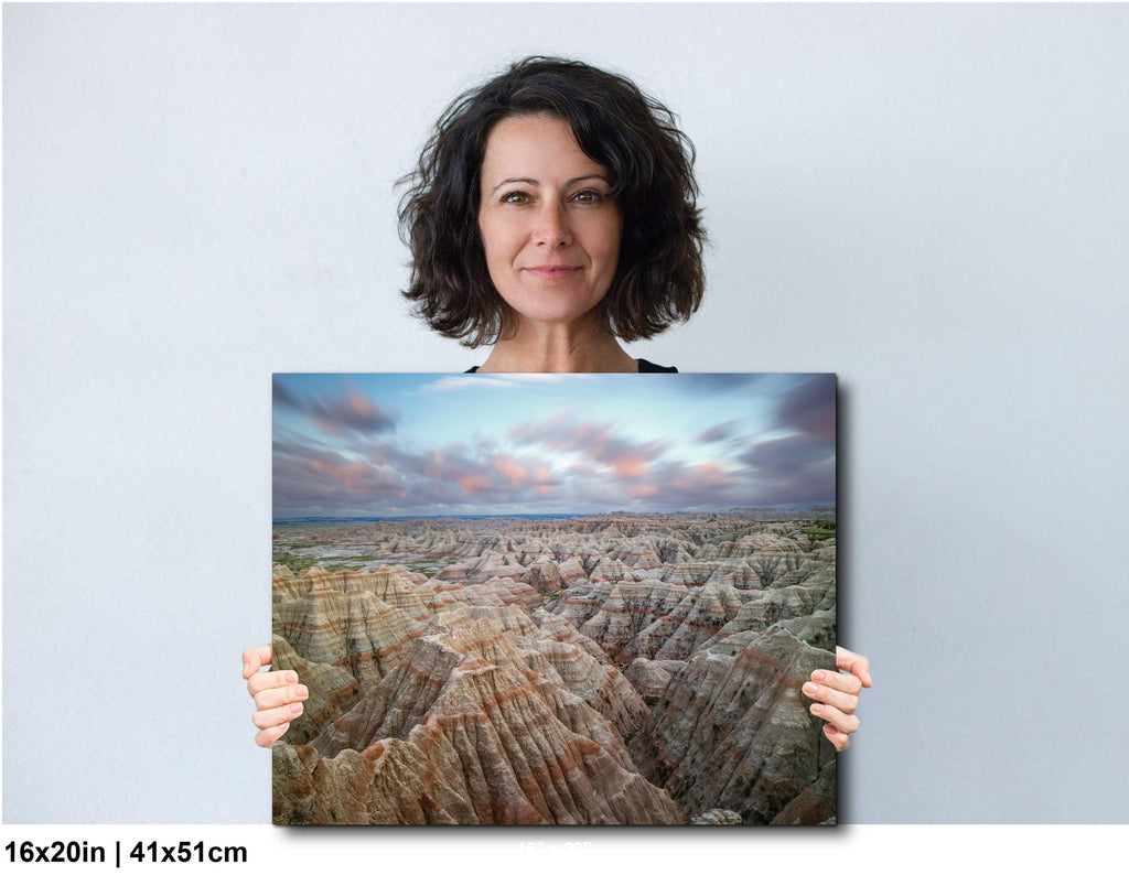 Woman holding a large landscape photo of a desert canyon with a blue sky.