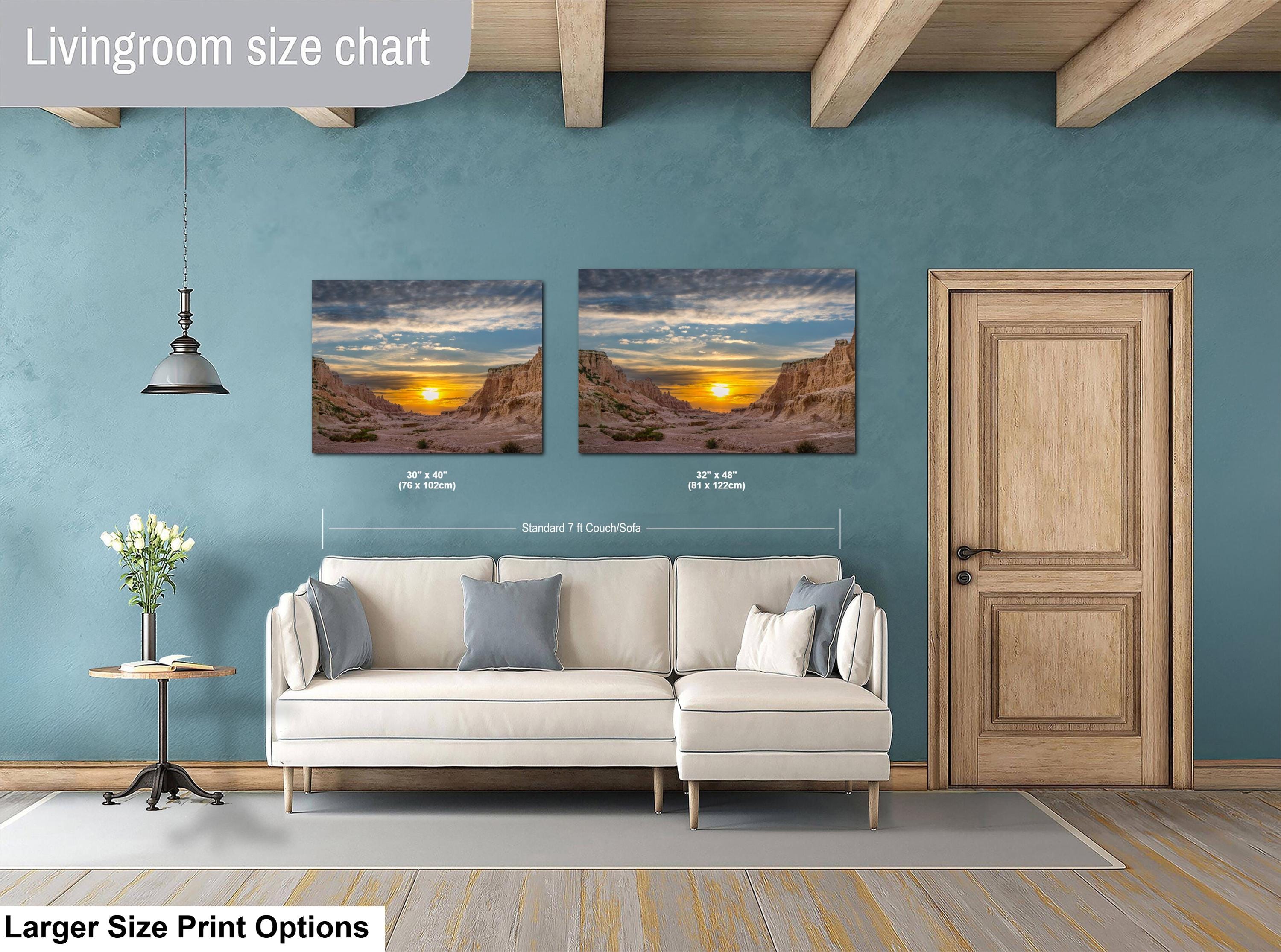 Living room with two wall art prints of a sunset over a mountain landscape, a beige sofa, and a wooden door.