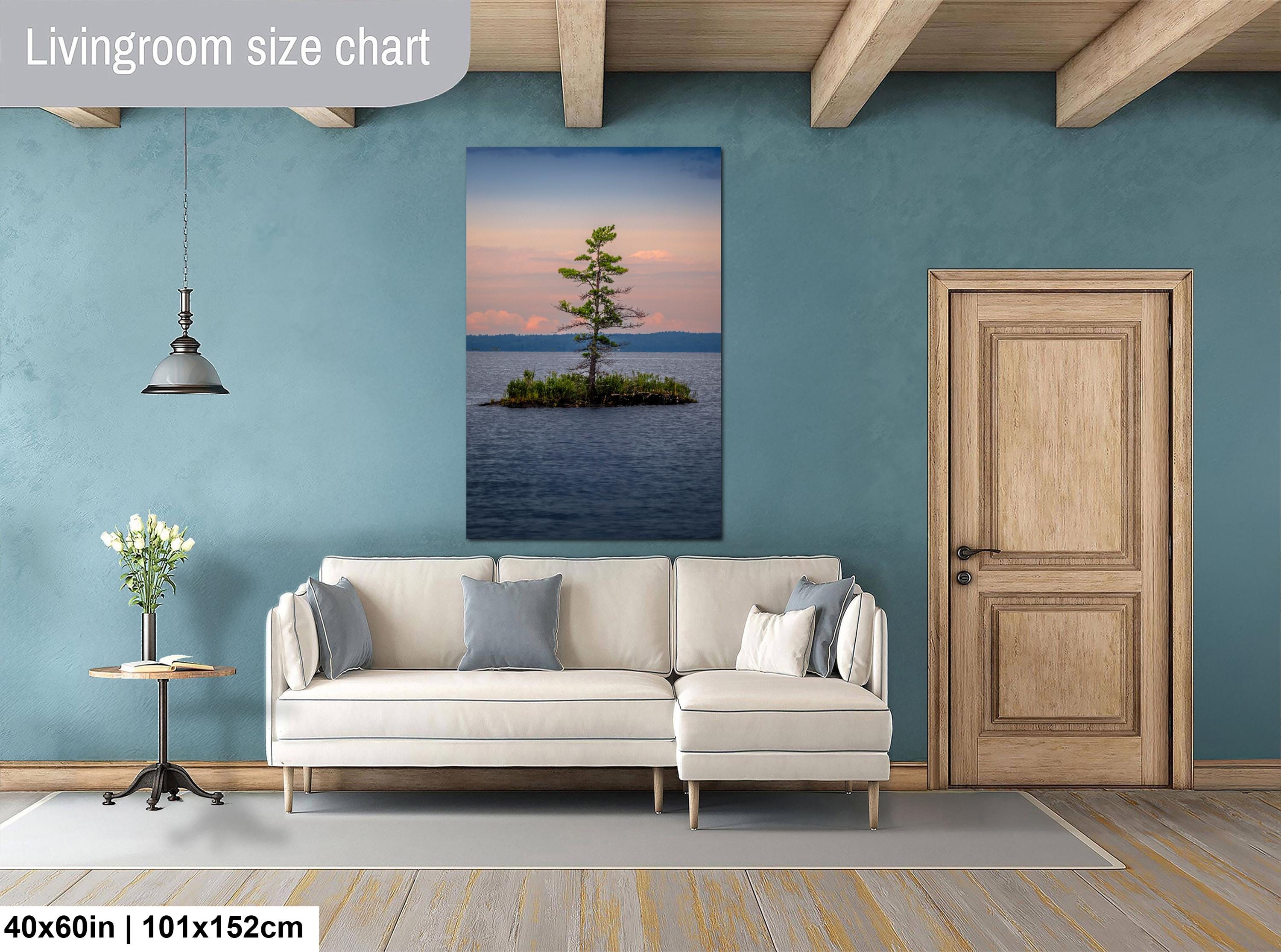 Living room with a beige sofa, side table, and wall art of a tree on an island.