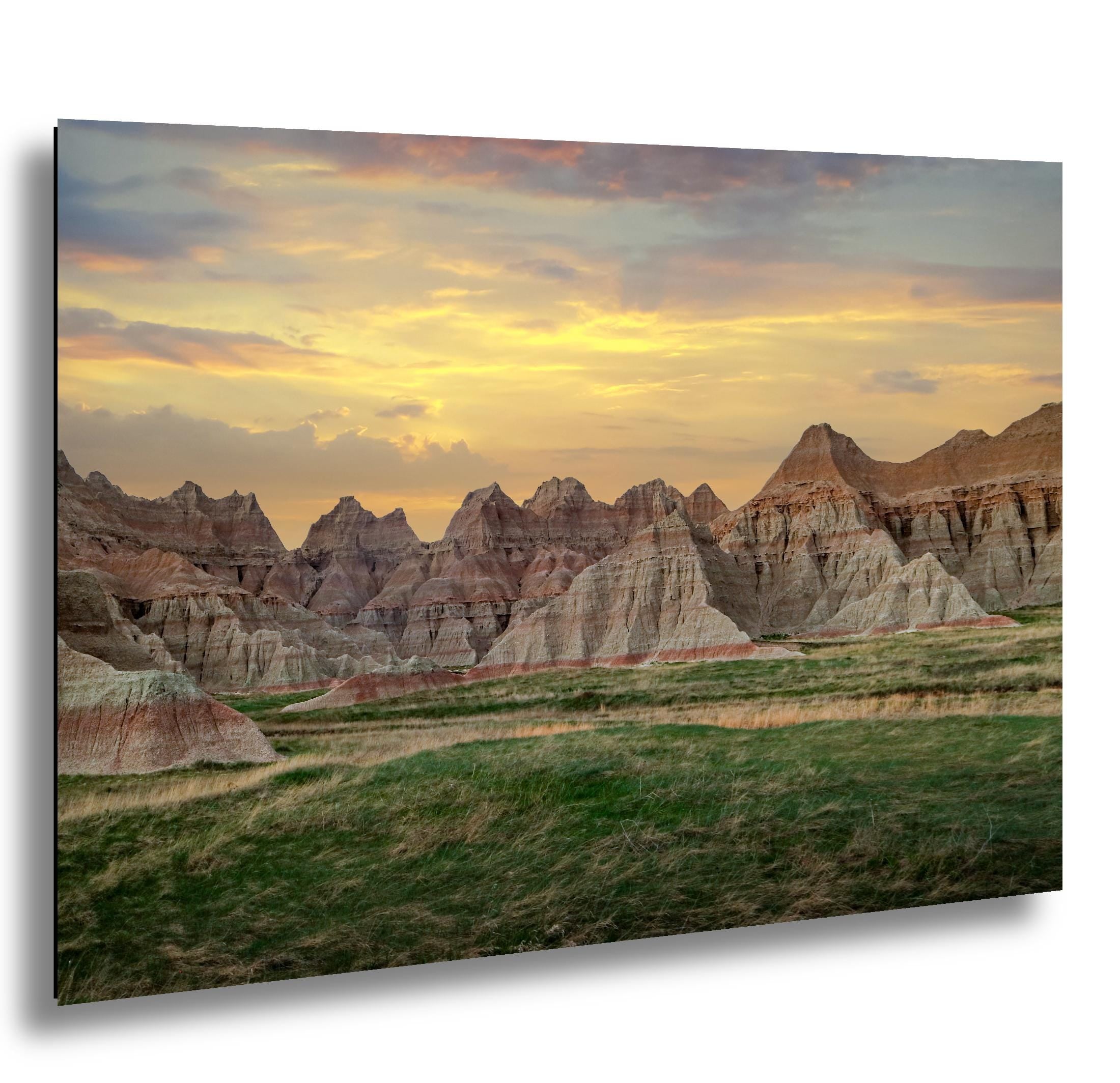 Badlands spires at sunset above prairie grass under golden sky, South Dakota panorama