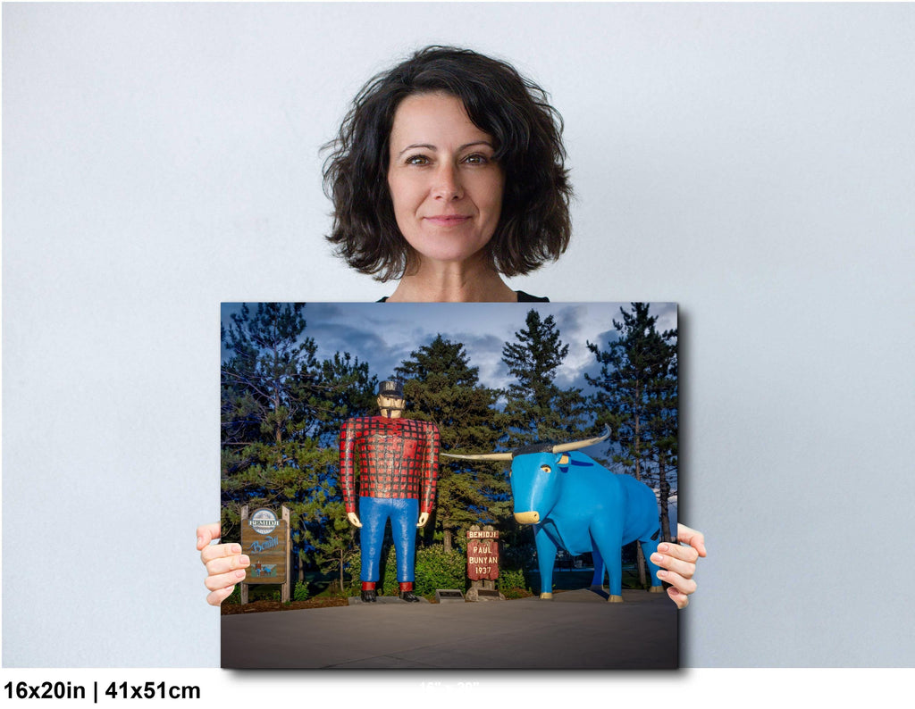 Woman holding a photograph of a man in plaid shirt and blue elephant statue against a white background