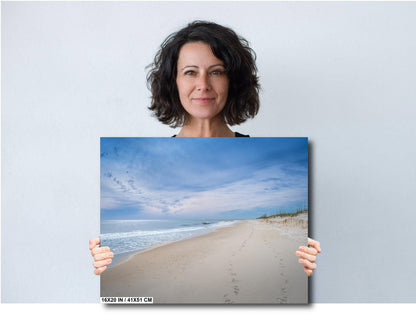 Woman holding a 16x20 beach photography canvas print of footprints in the Sands of Perdido Key.