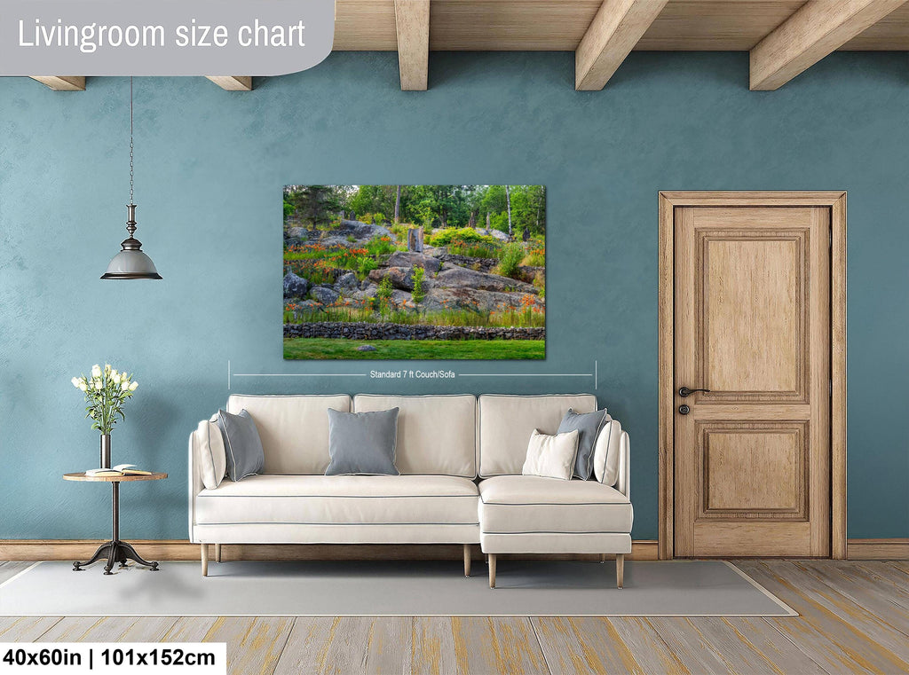 Living room with a beige sofa, side table, and wall-mounted wall art displaying a nature scene at Ellsworth Rock Gardens