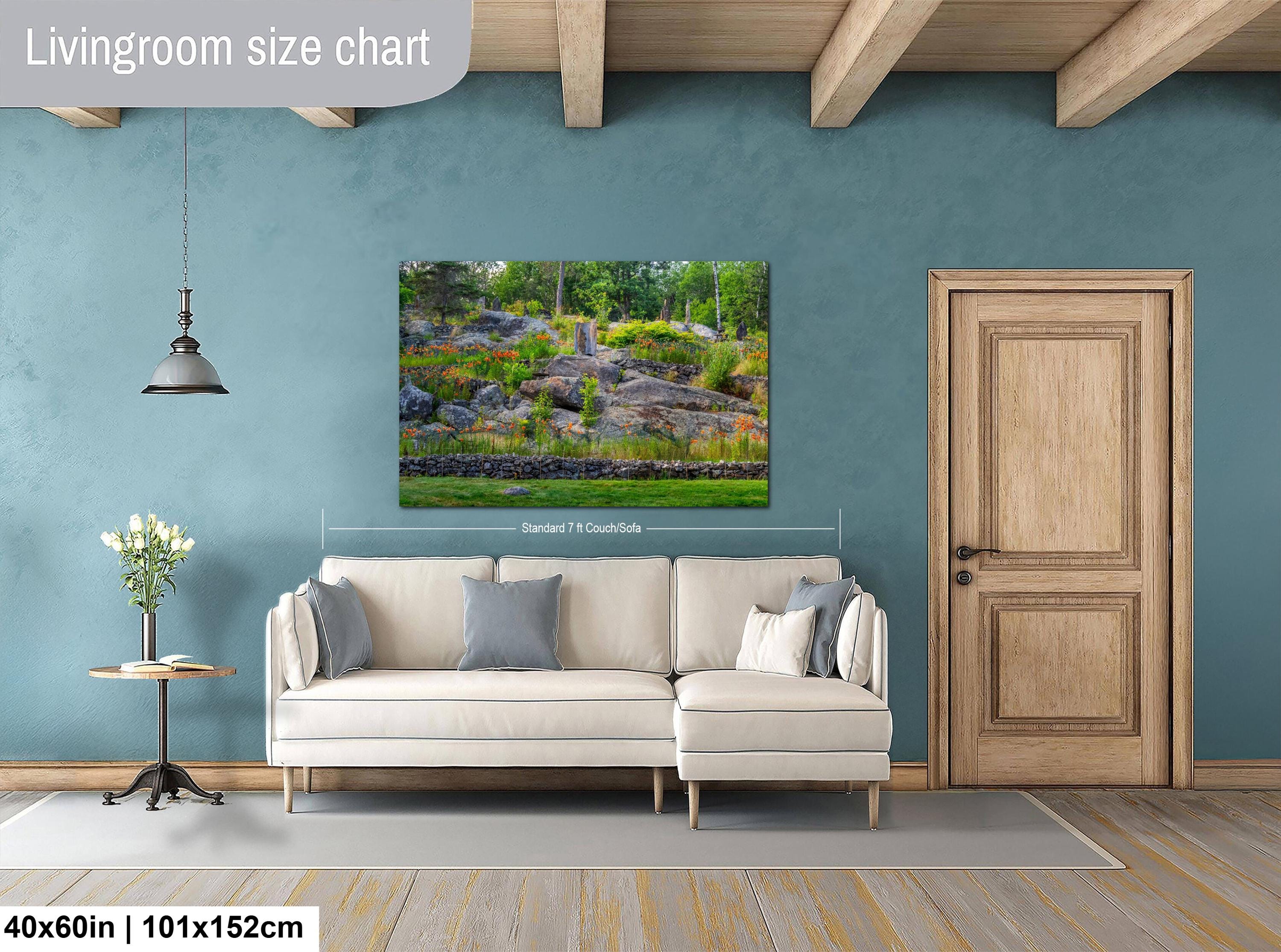 Living room with a beige sofa, side table, and wall-mounted wall art displaying a nature scene at Ellsworth Rock Gardens