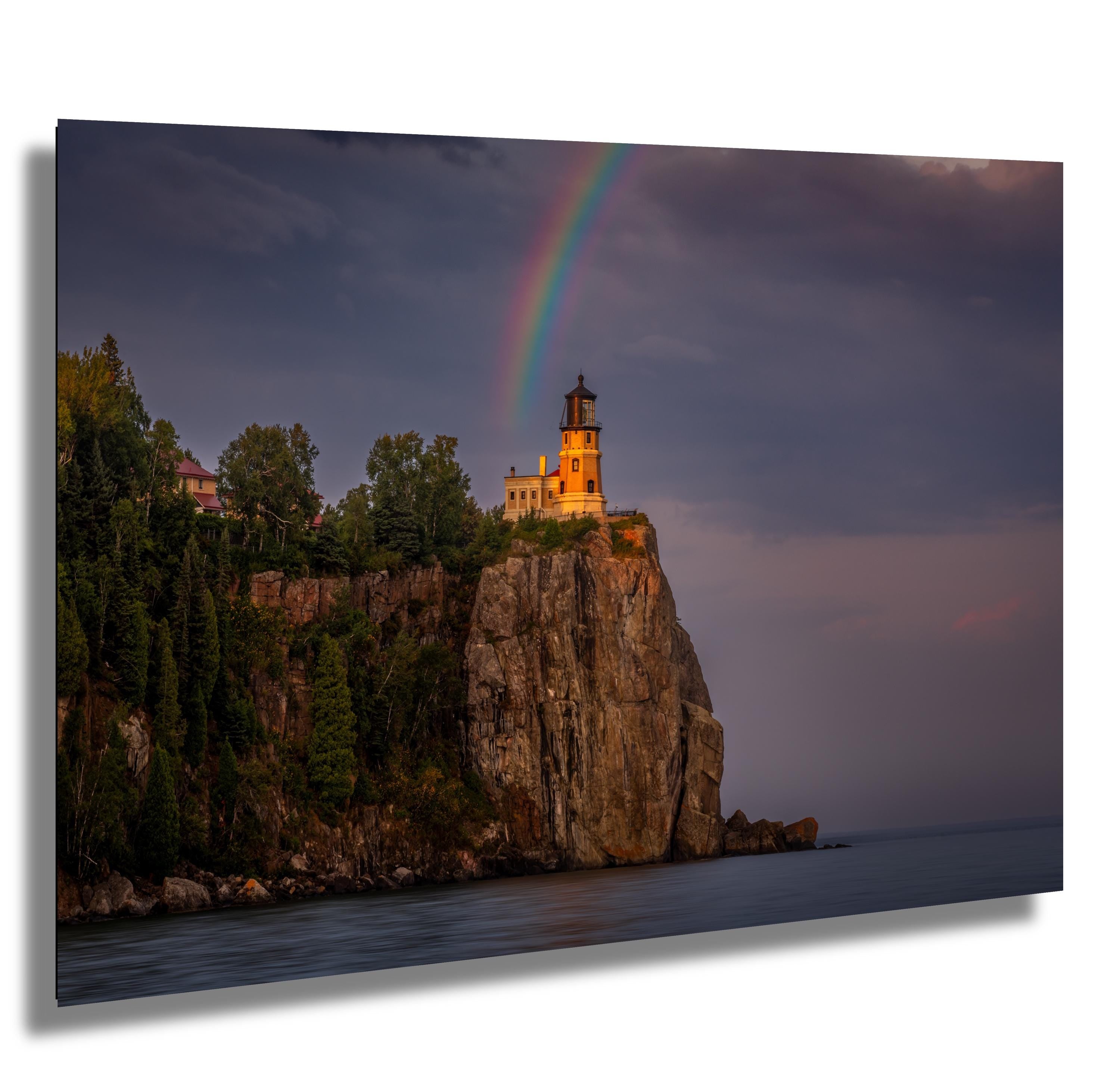 Rainbow arches over Split Rock Lighthouse, framed by cliffs and Lake Superior.