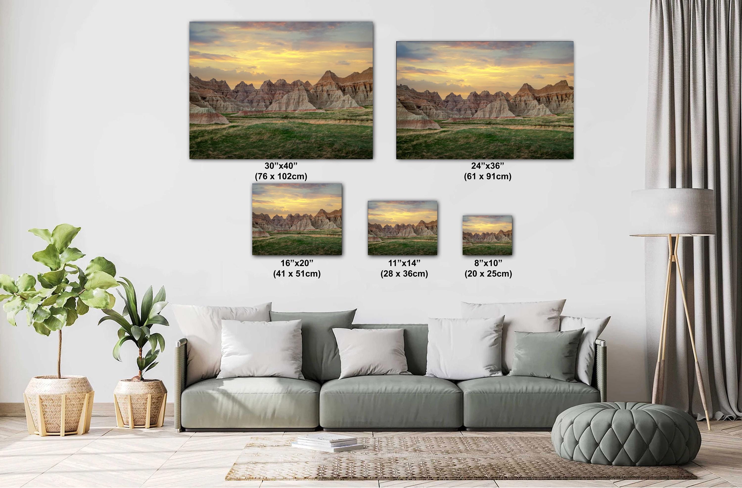Living room with a sofa and decorative plants, featuring wall art of mountain landscapes with measurements.