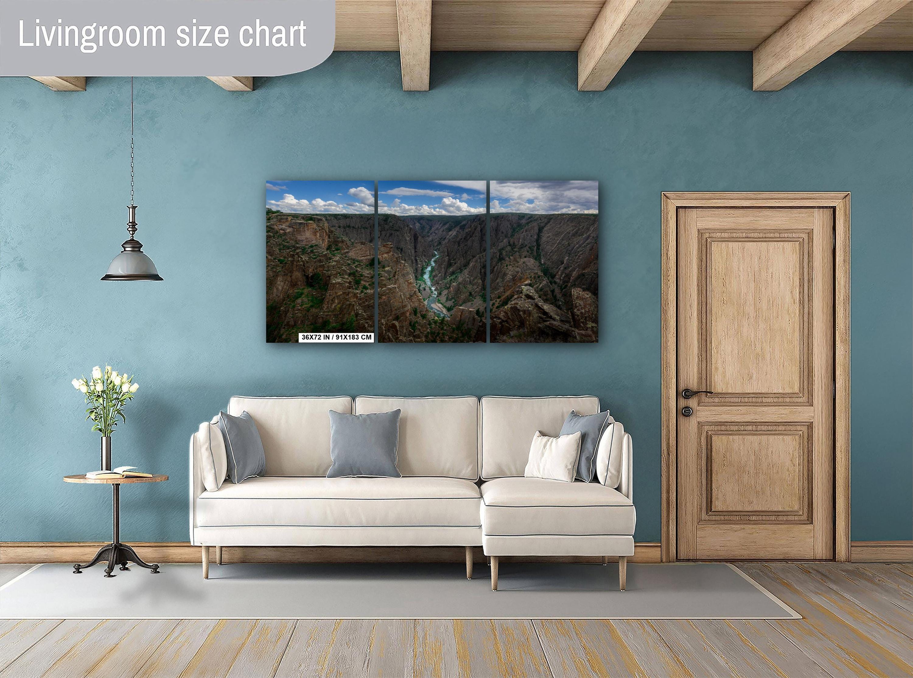 Living room with a large wall-mounted nature-themed triptych painting, beige sofa, and wooden door.