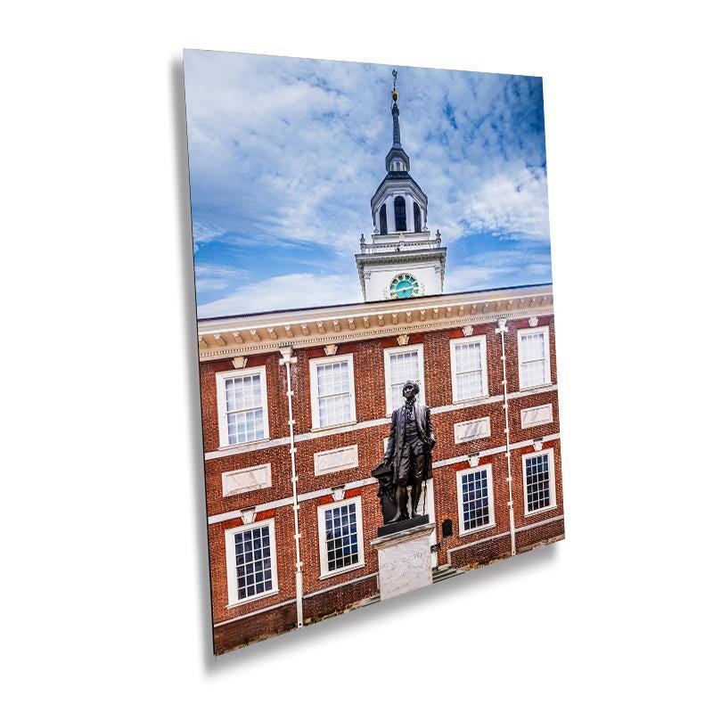 A wall art print featuring a statue of George Washington at Independence Hall, with a clear blue sky and white-framed windows in the background.