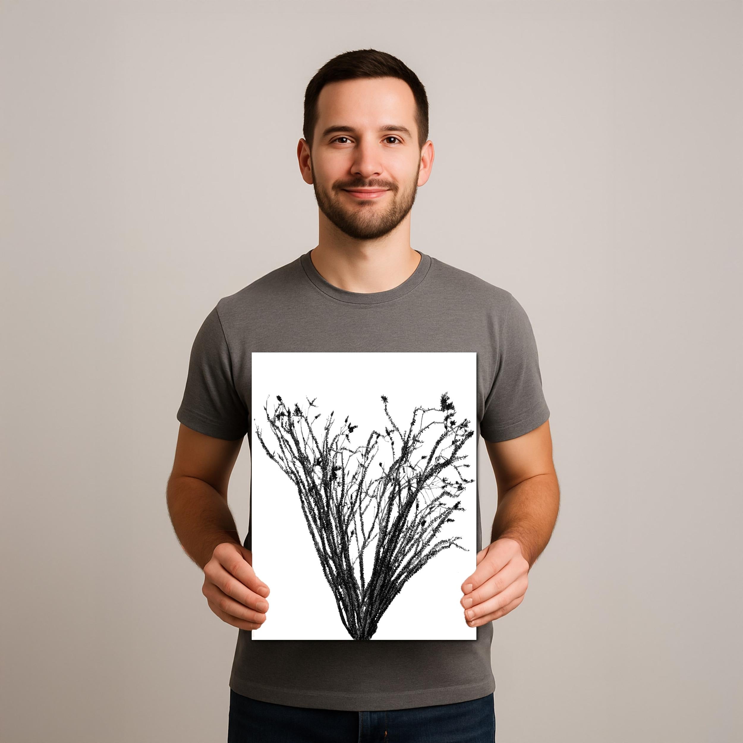 Man holding a black and white print of tree branches against a plain background