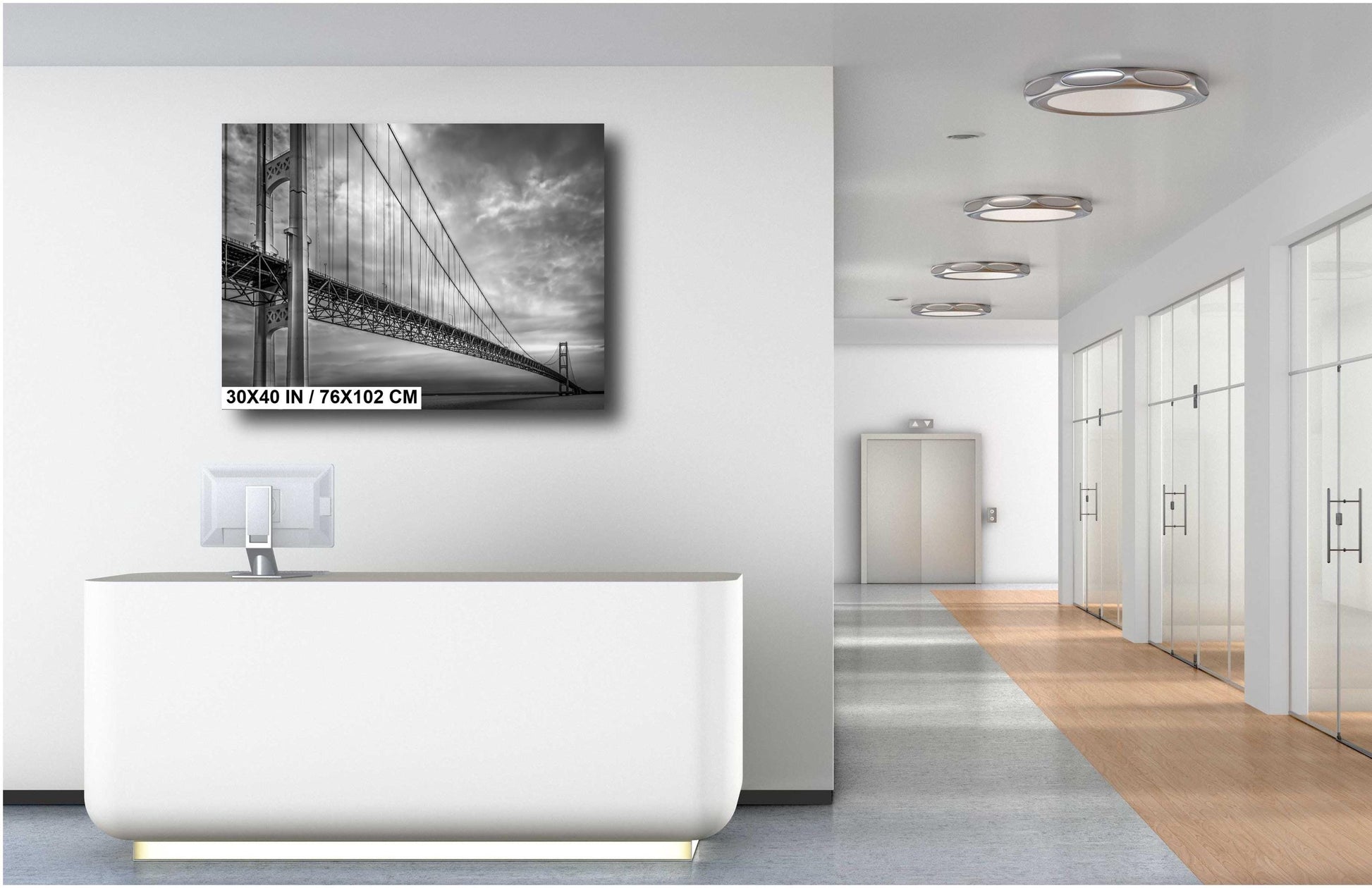 A black and white photograph of the Mackinac Bridge, capturing the engineering and grandeur of the structure with a backdrop of overcast sky and a body of water.