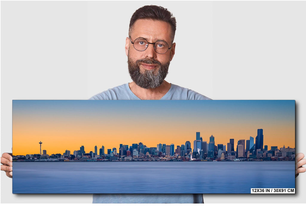 Man holding a large canvas print of a city skyline with a blue and orange gradient.