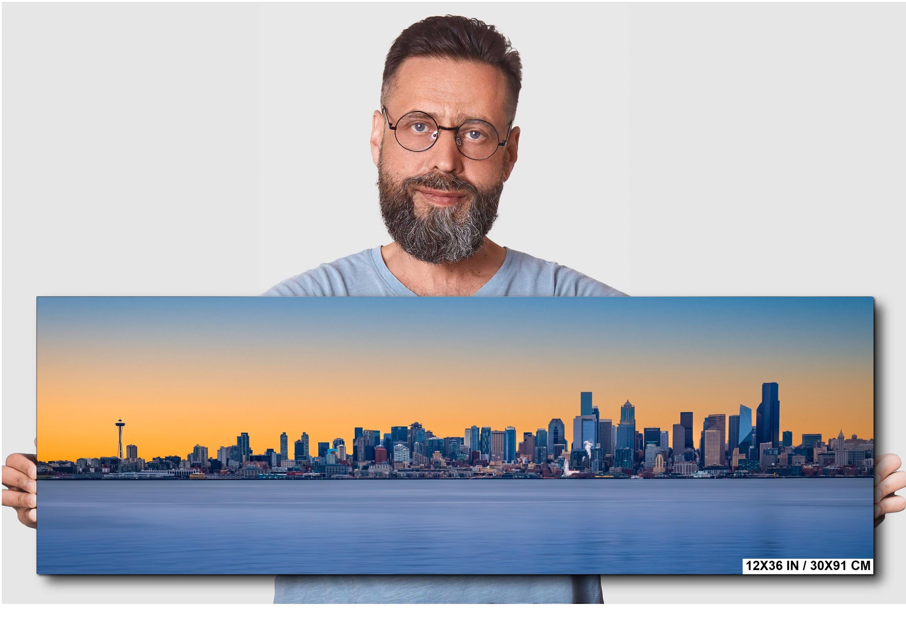 Man holding a large canvas print of a city skyline with a blue and orange gradient.