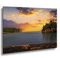 Split Rock Lighthouse at sunset above calm Lake Superior, glowing cliffs and pebble beach