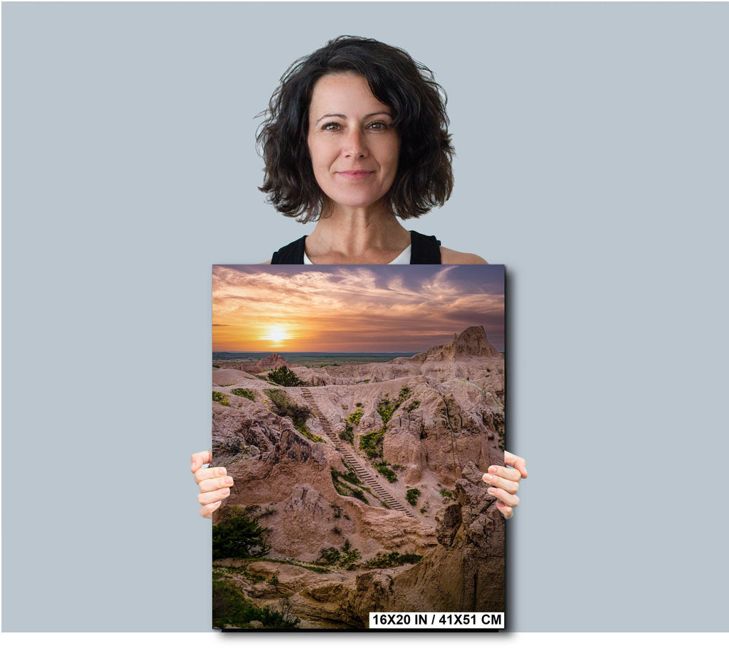 Woman holding a photograph of a sunset over a landscape