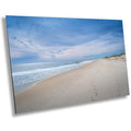 A wall art print featuring a beach scene with footprints on the sand, the ocean, and a clear sky.