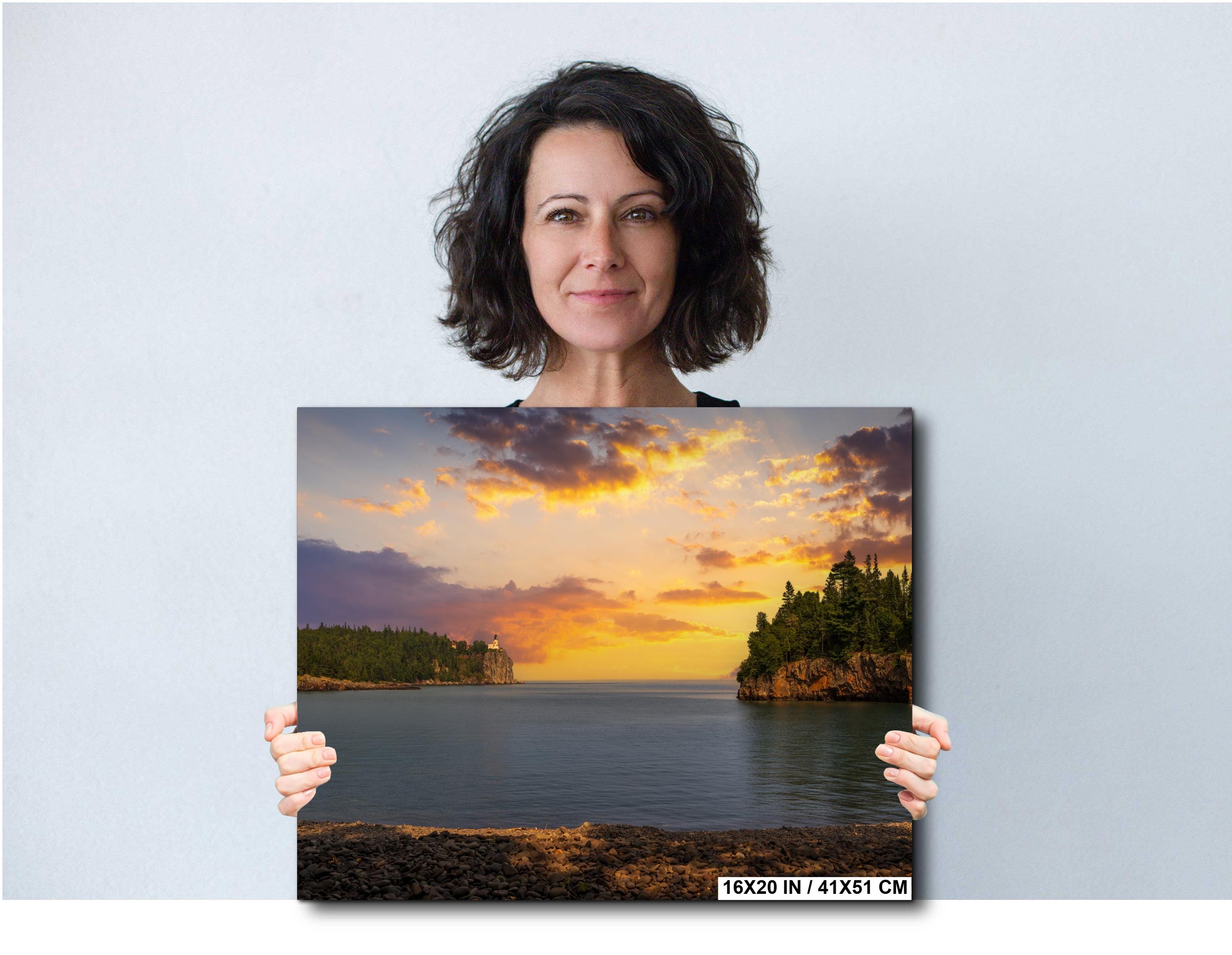 Woman holding a photograph of a sunset over water