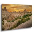 Badlands National Park sunset with yellow wildflowers in foreground and glowing cliffs.