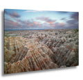 Badlands National Park layered rock formations at sunset with soft clouds above.