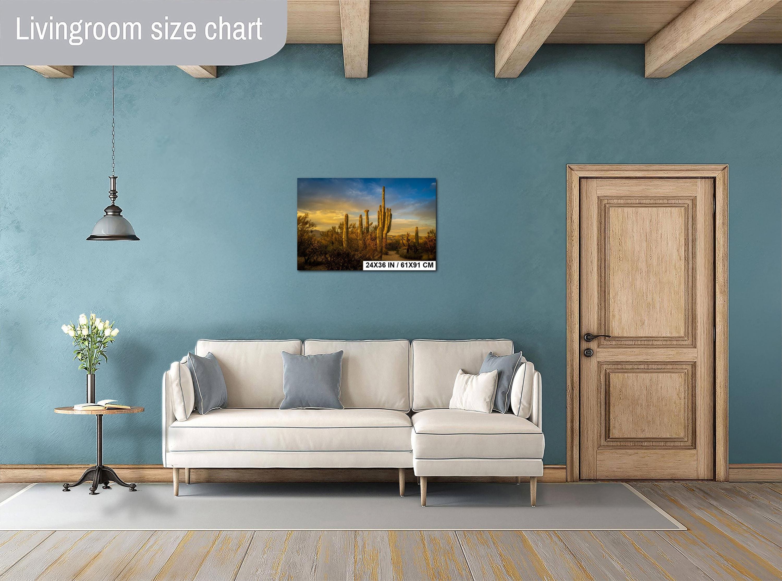 Living room with a beige sofa, decorative pillows, a small table with a plant, and a painting on the wall.