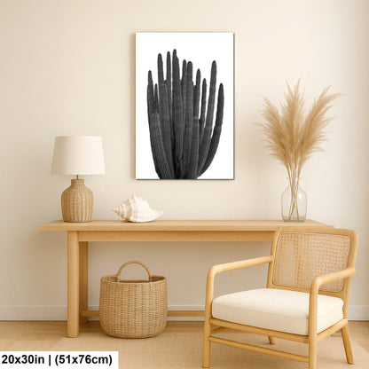 Black and white wall art print of an organ pipe cactus with tall vertical arms and ribbed detail in a nautical-themed room with a wooden table, wicker chair, and decorative items.