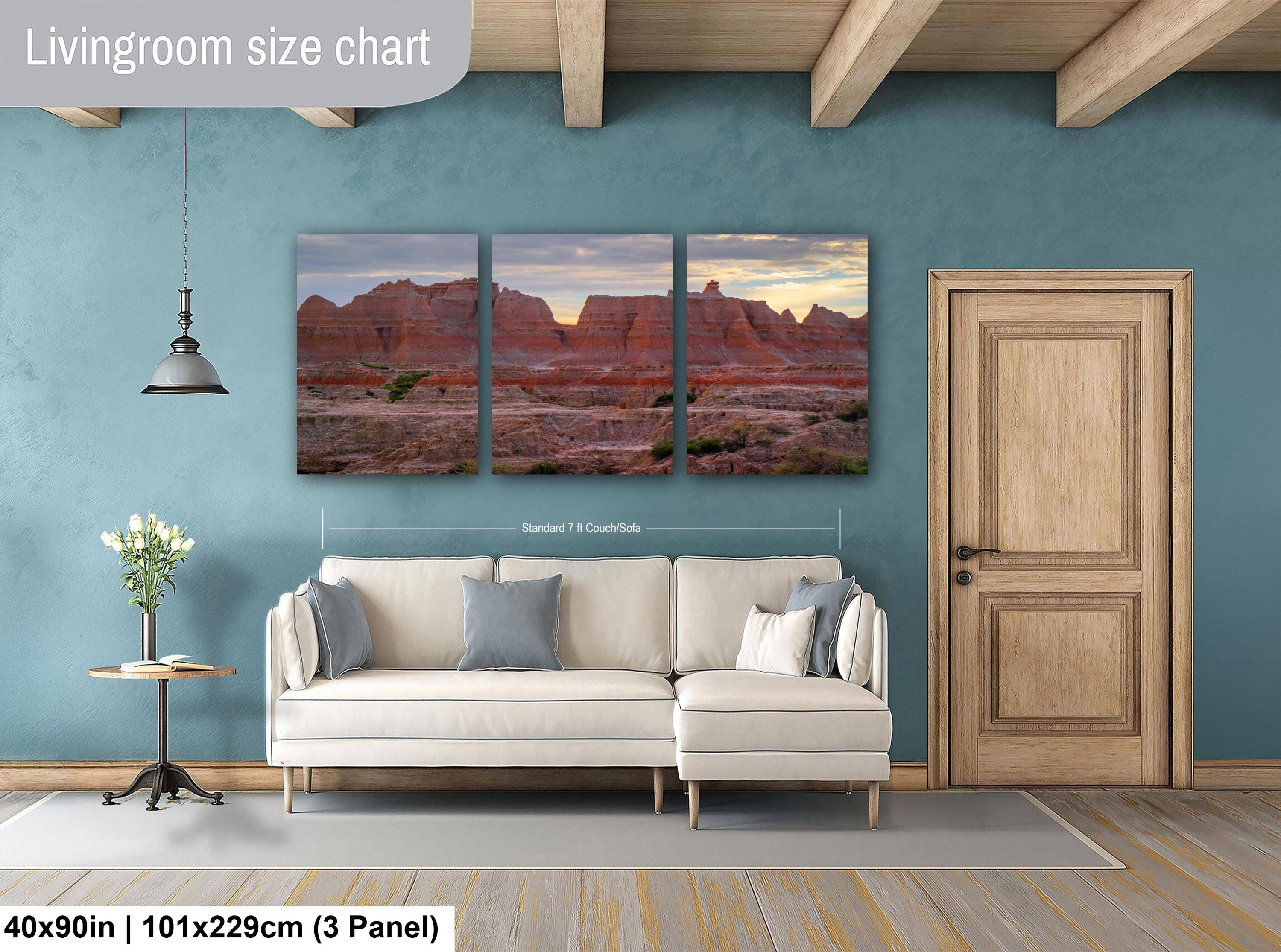 Living room with a beige sectional sofa, side table, and three-panel wall art of desert landscapes.