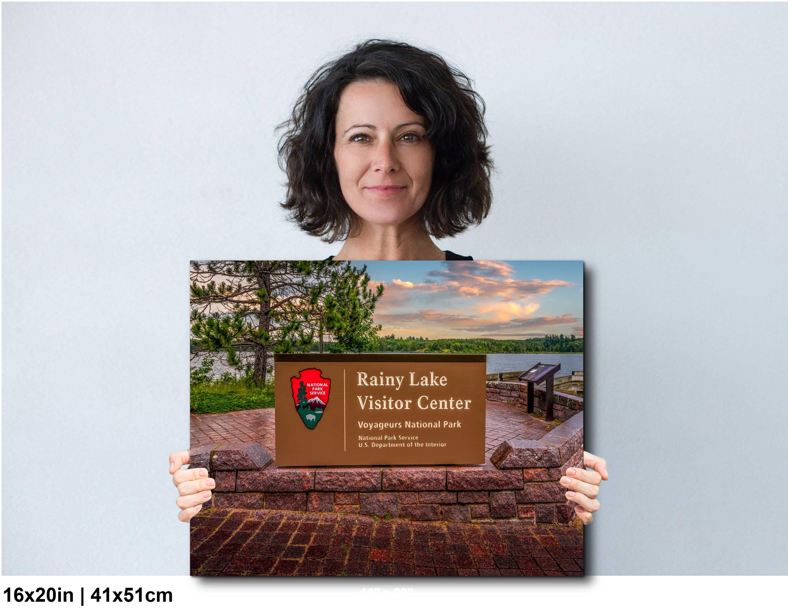 Woman holding a print of Rainy Lake Visitor Center with a scenic background