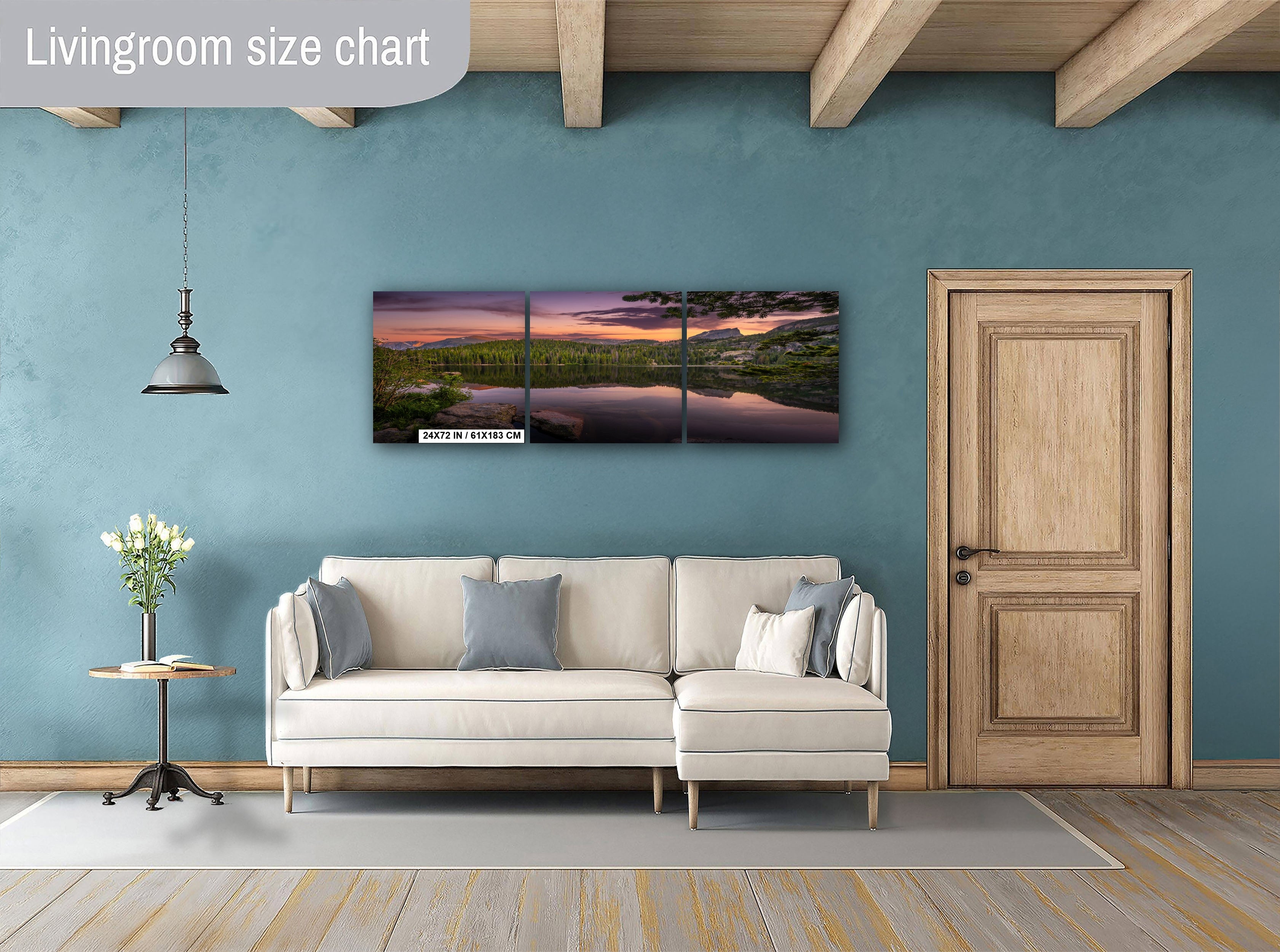 a living room with a white sofa, a wooden door, and a large wall art piece depicting a serene landscape with a lake and mountains.
