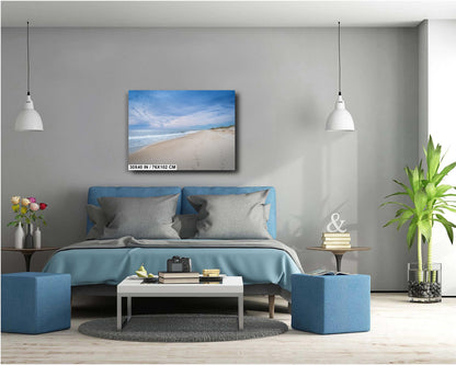 A wall art print featuring a beach scene with footprints on the sand, the ocean, and a clear sky.