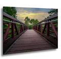 Rust-red footbridge at sunset leading through green trees in Gooseberry Falls State Park.