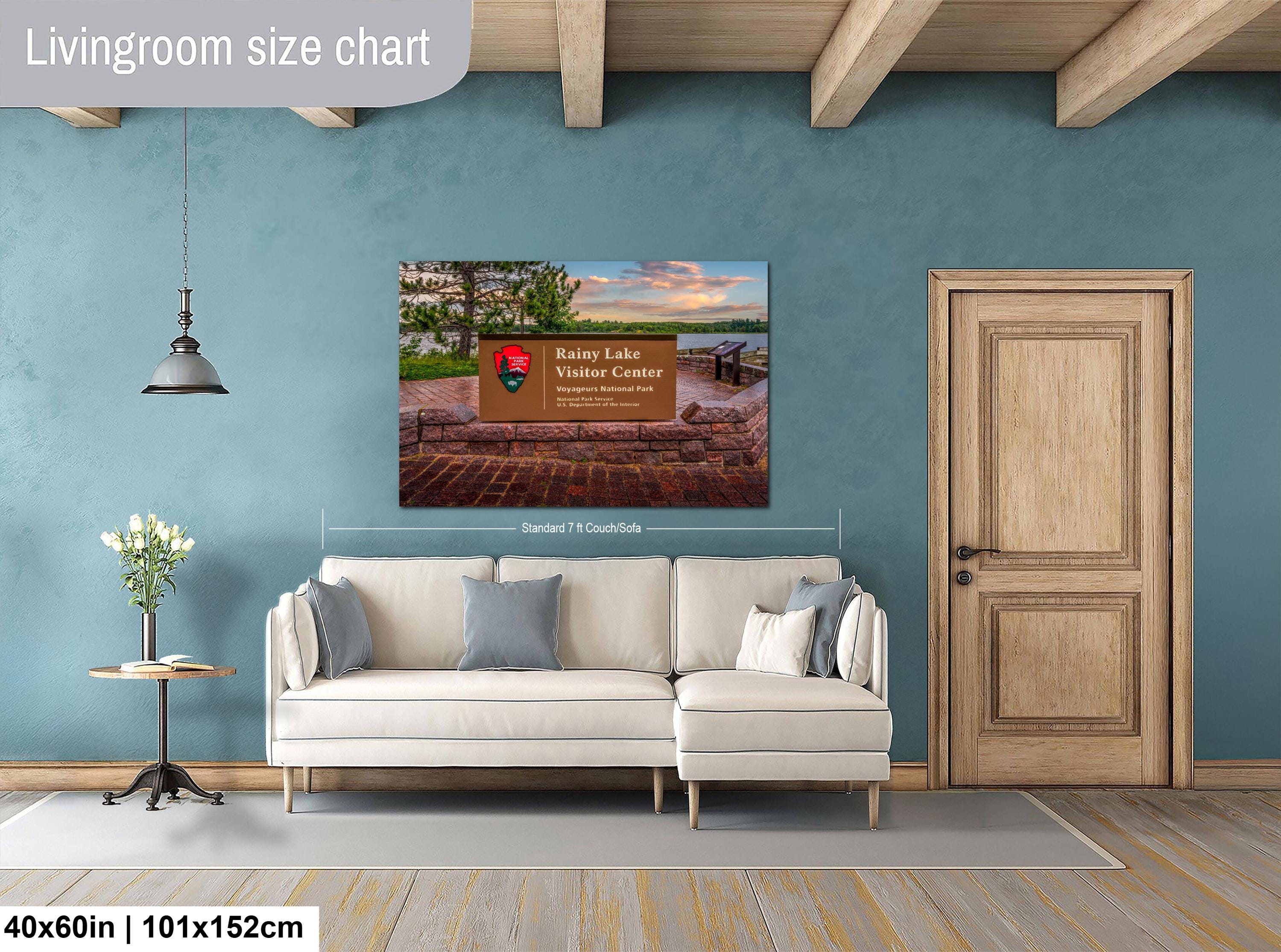 Living room with a wall art displaying a scenic view, beige sofa, and wooden door.