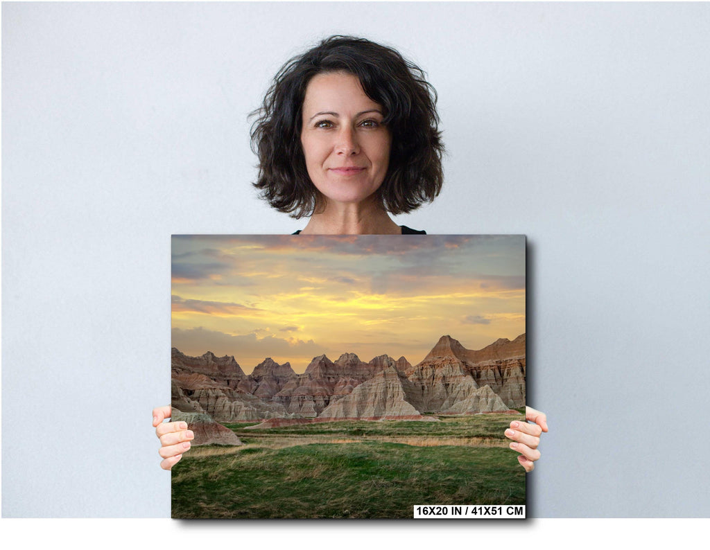 Woman holding a photograph of a mountain landscape with a sunset.