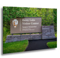 Rainy Lake Visitor Center sign at Voyagers National Park with stone structure and greenery.